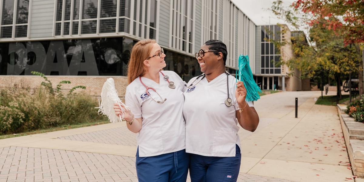 AACC students wearing scrubs and posing outside Library.